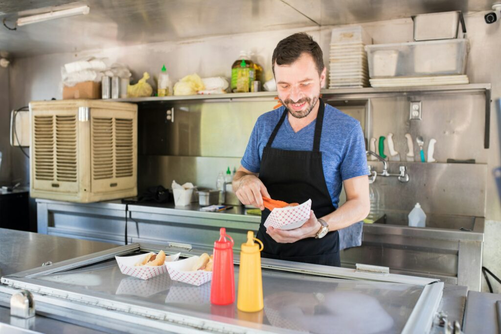 man preparing a hot dog in a concession stand