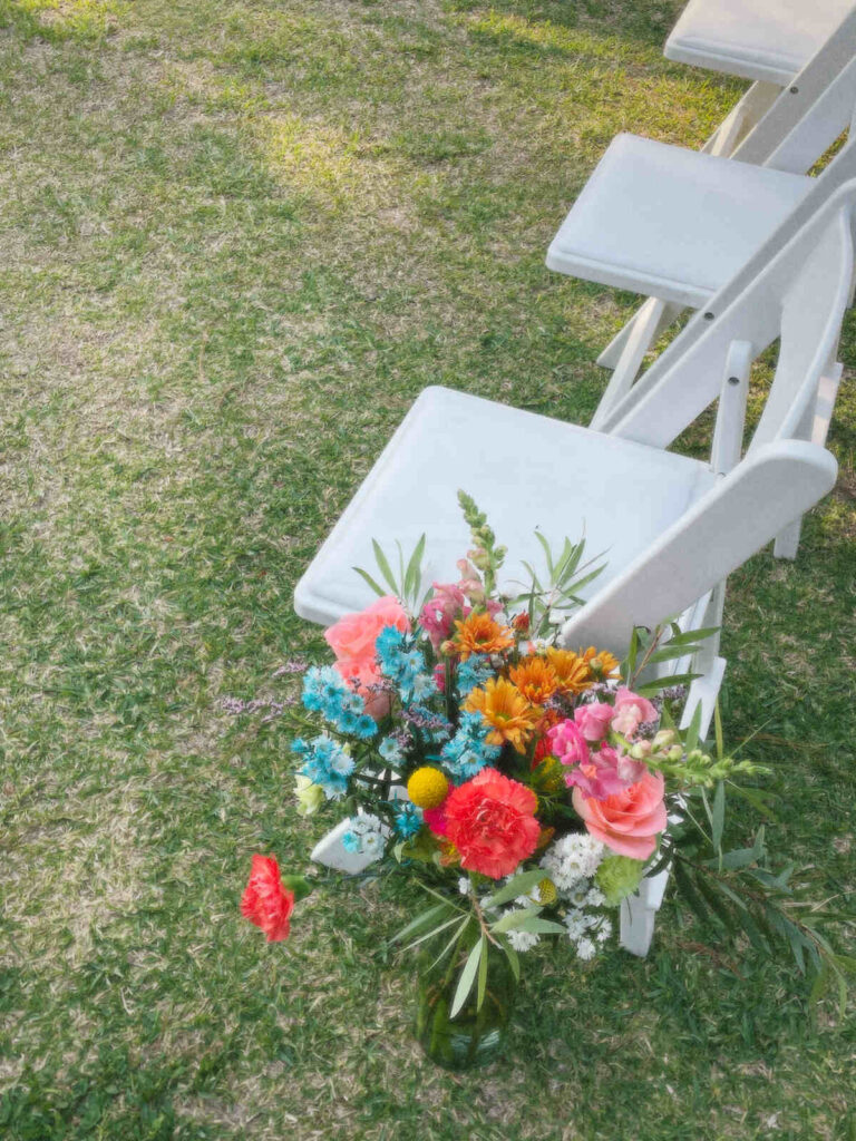 White padded folding chair next to flowers